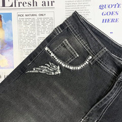 Vaqueros oscuros con bordado de calavera gótica