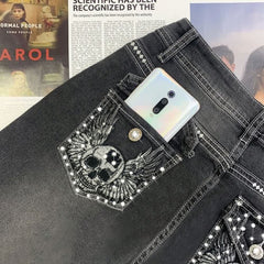 Vaqueros oscuros con bordado de calavera gótica