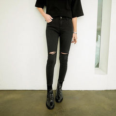 Pantalones elásticos negros con agujeros rotos por encima de la rodilla