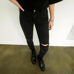 Pantalones elásticos negros con agujeros rotos por encima de la rodilla