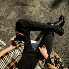 Pantalones elásticos negros con agujeros rotos por encima de la rodilla