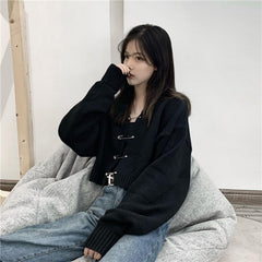 Suéter negro holgado y corto con alfileres enormes y atrevidos