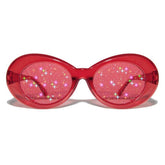 Gafas de sol ovaladas con montura de plástico brillante y lentes transparentes con purpurina
