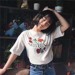 Camiseta blanca con letras Nothing y rosas rojas y flores