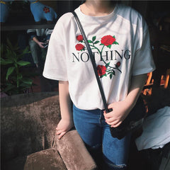 Camiseta blanca con letras Nothing y rosas rojas y flores