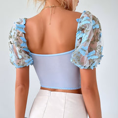 Top corto de malla con mangas abullonadas y bordado floral en azul pastel